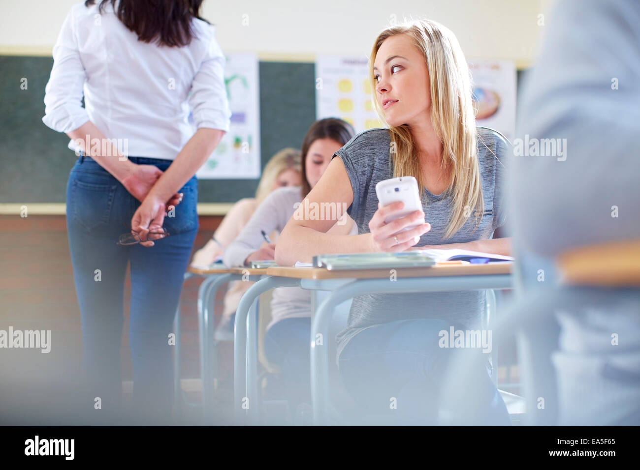 Female student in classroom cheating during an exam Stock Photo