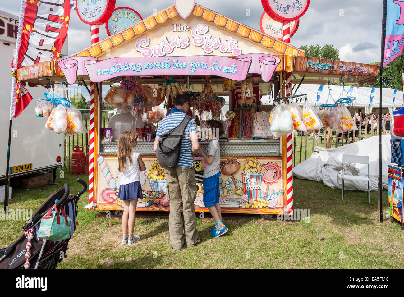 Man buying sweets for children from a stall selling sugary snacks at an English summer fair. Stock Photo