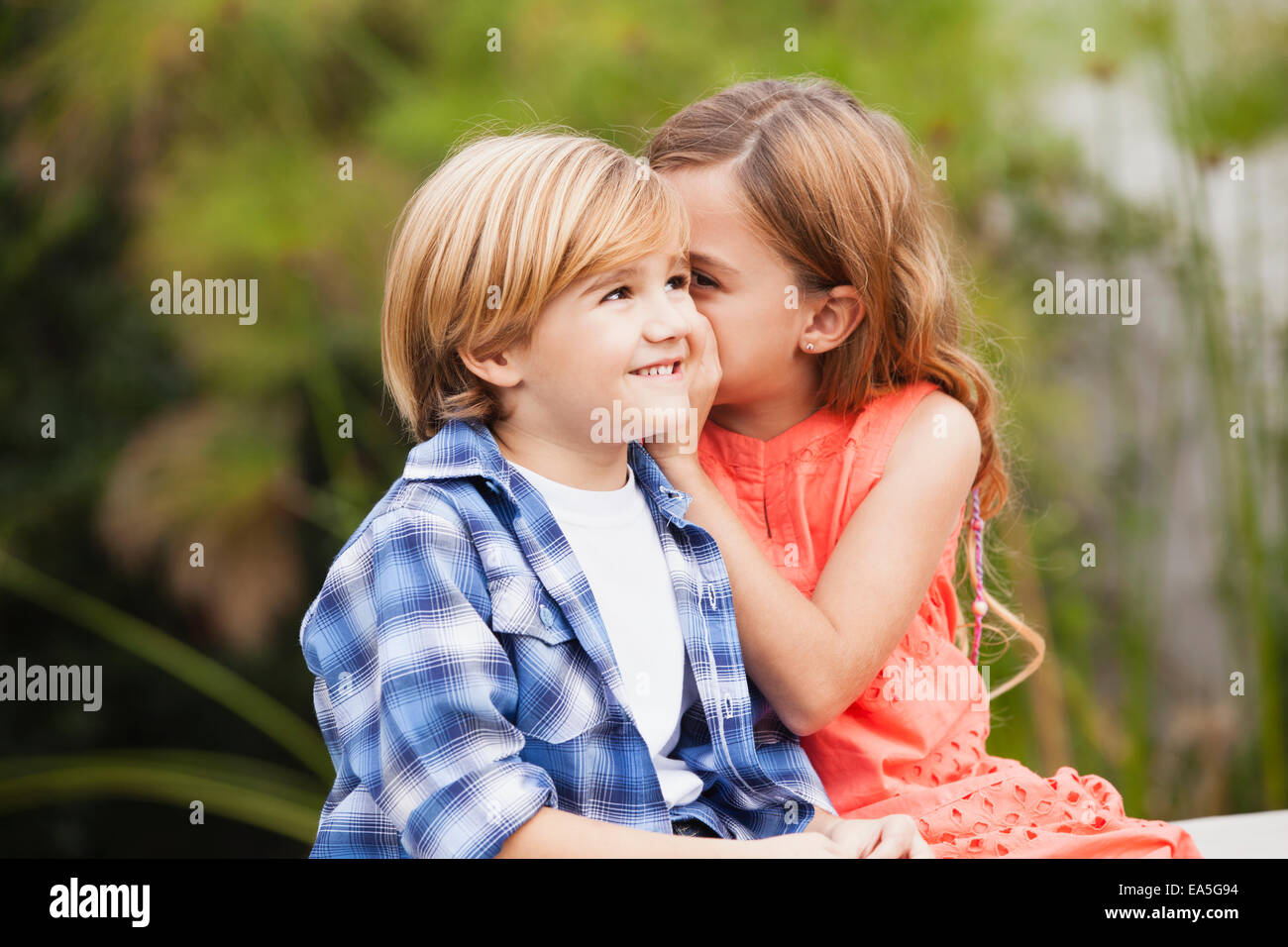 Girl whispering into boy's ear Stock Photo Alamy