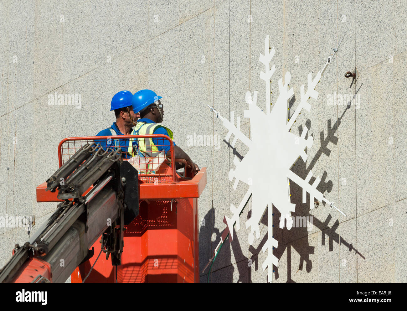 Las Palmas, Gran Canaria, Canary Islands, Spain. 7th November, 2014. Wormen installing snowflake christmas lights display on El Corte Ingles department store building in Las Palmas, Gran Canaria under blue skies and temperatures in the mid 20s C. El Corte Ingles is Spain`s largest department store chain. Credit:  ALANDAWSONPHOTOGRAPHY/Alamy Live News Stock Photo