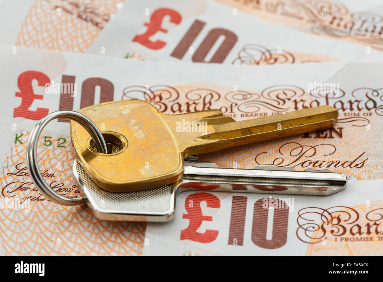 House keys on money sterling ten pound notes GBP to illustrate UK property prices savings and investment concept. England, UK, Britain Stock Photo
