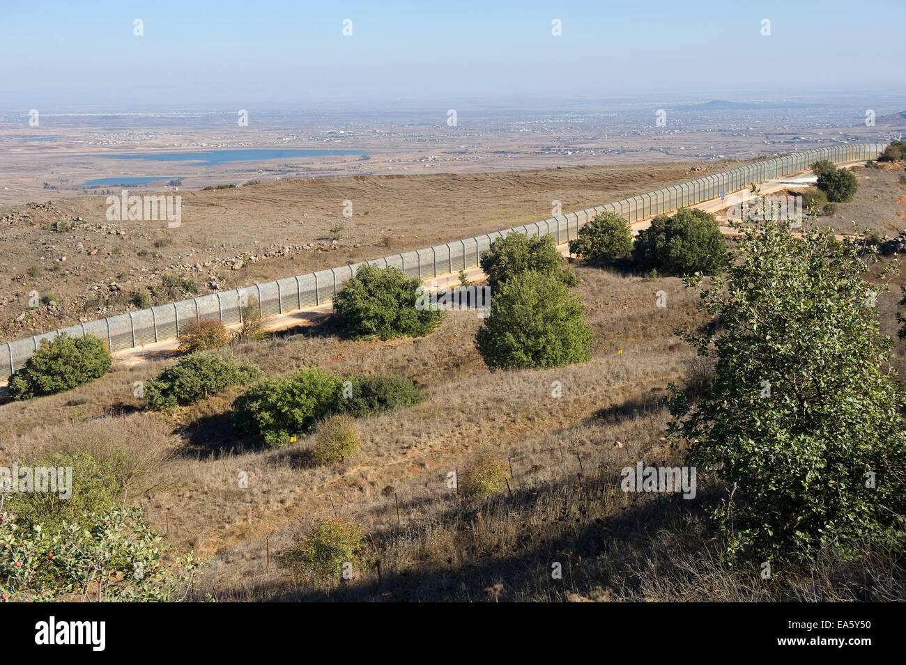 The fence of the border between Israel and Syria as seen from a hill on the Golan Heights in Israel Stock Photo