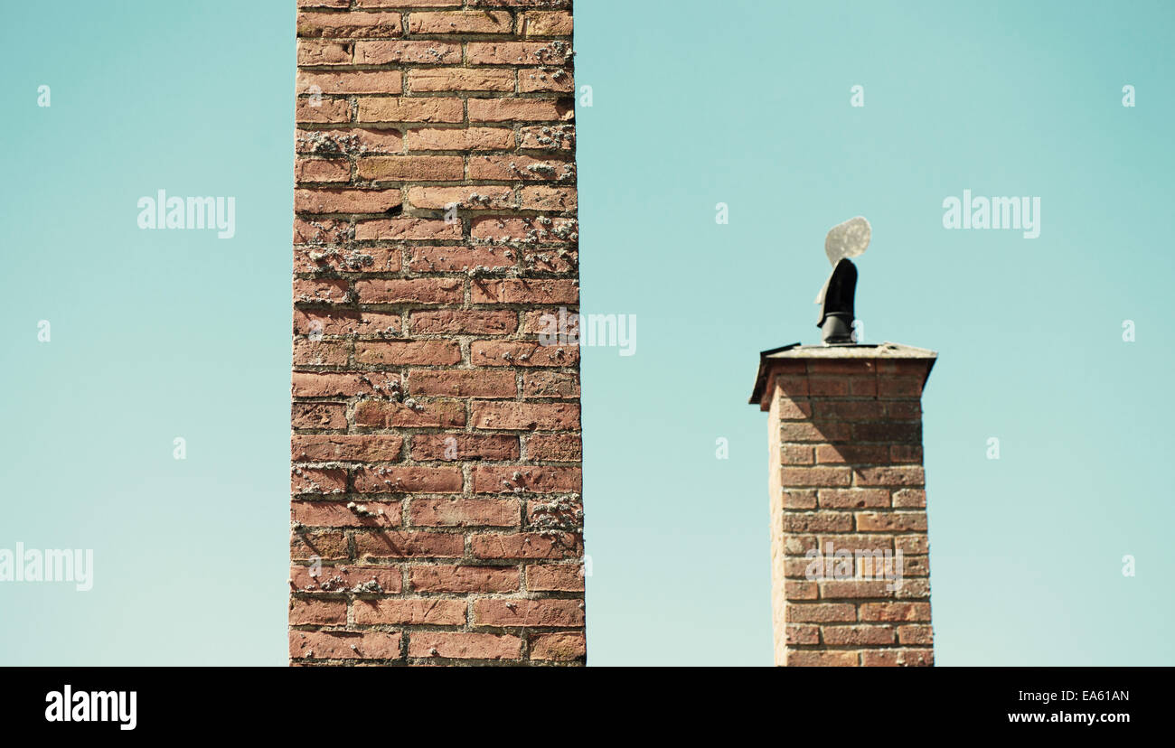 Two brick chimneys, one tall and one short. Stock Photo