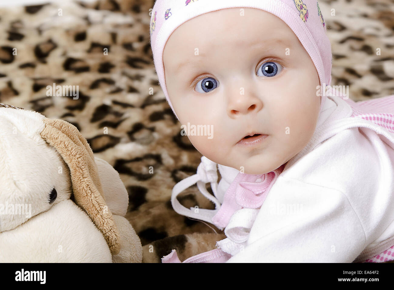 surprised baby in a cap with a soft toy Stock Photo