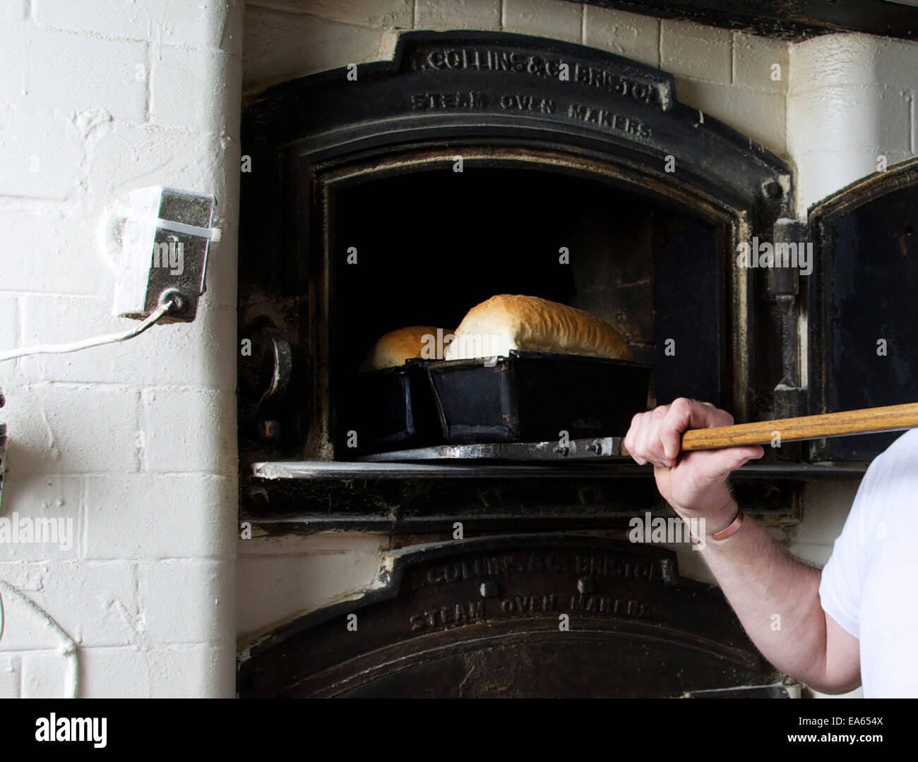 Freshly baked bread being removed from a traditional, old oven by a local baker. Stock Photo