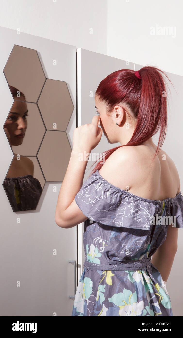 Beautiful young woman looking in mirror Stock Photo - Alamy