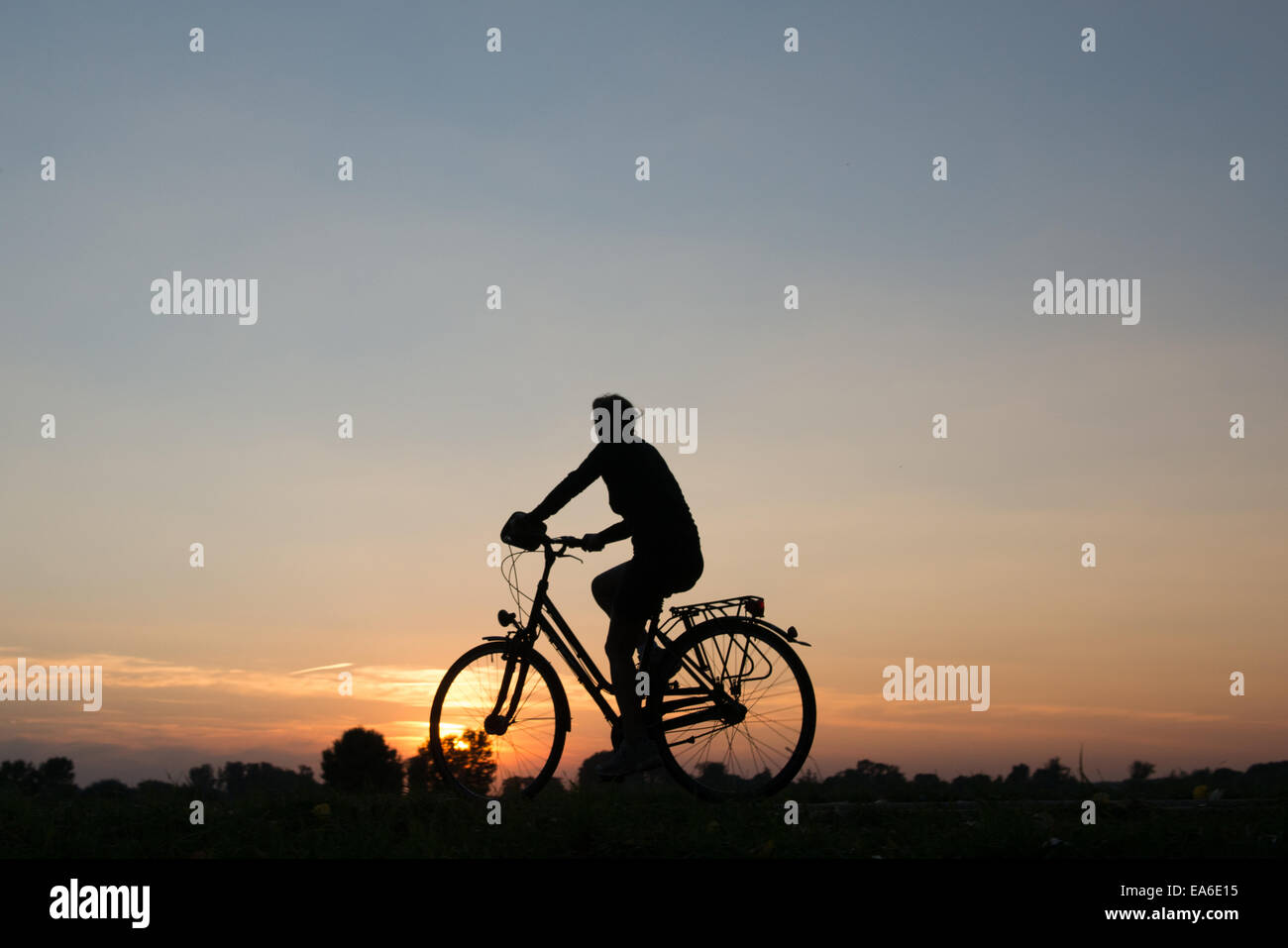 Germany, North Rhine-Westphalia, Cycling at sunset along Rhein River Stock Photo