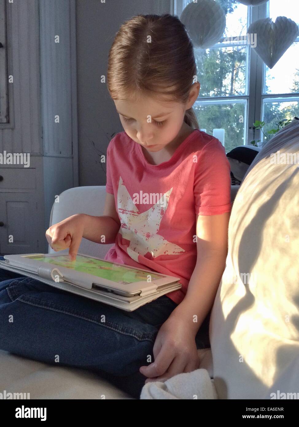 Girl sitting on the sofa using a digital tablet Stock Photo - Alamy