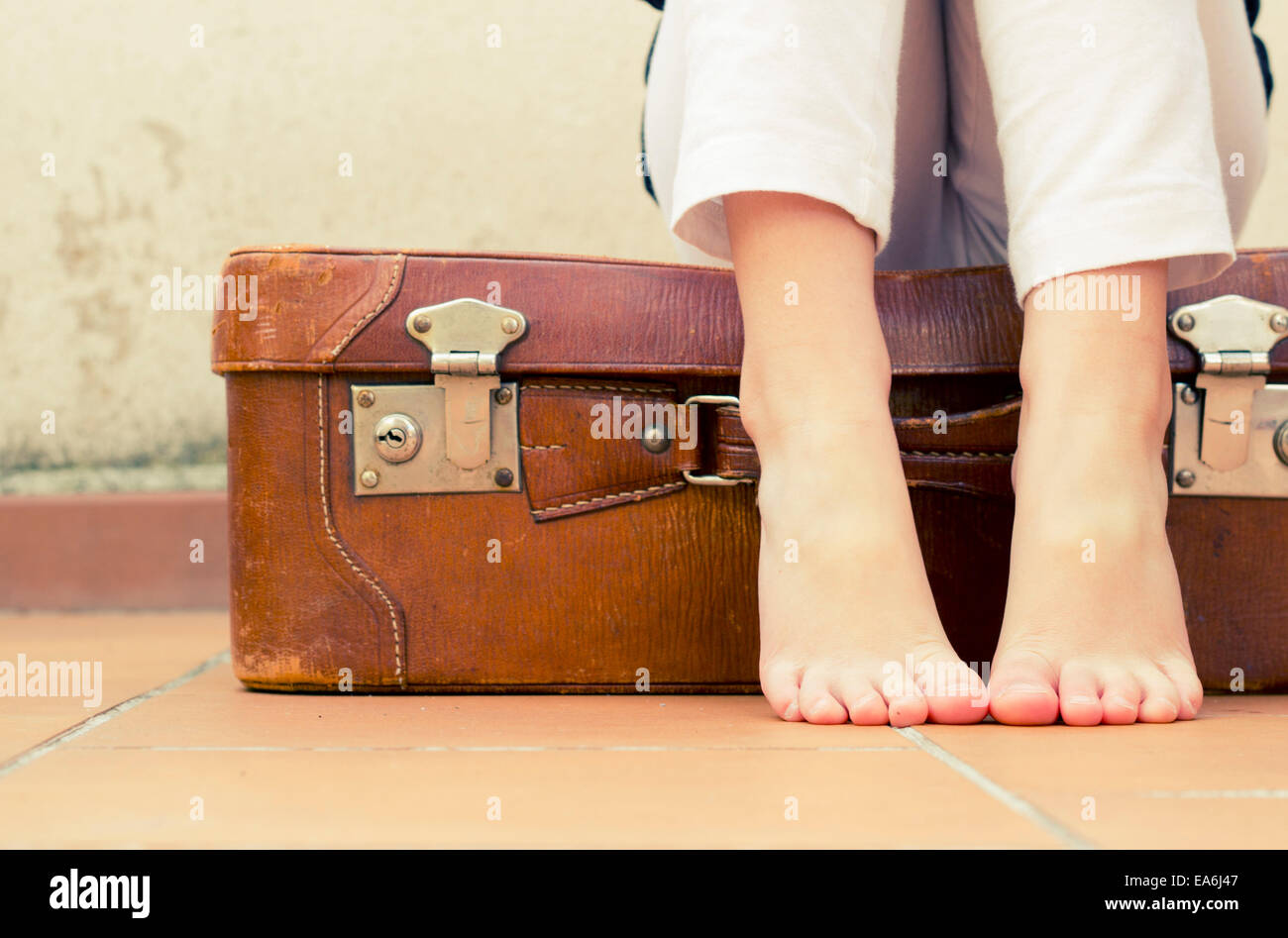 Girl sitting on a suitcase Stock Photo