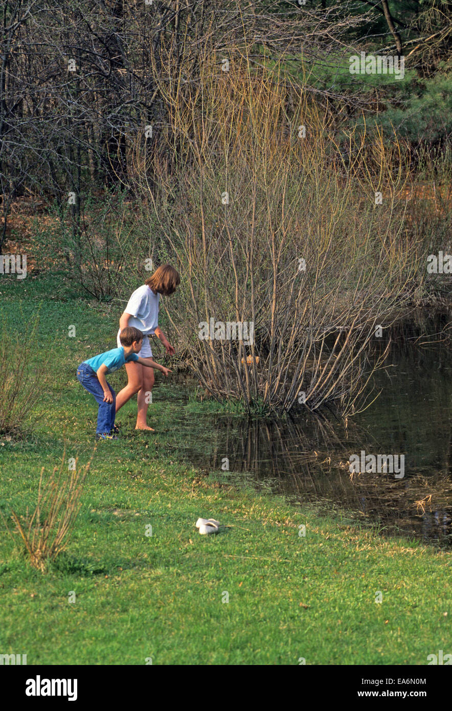 Two children play near a pond in Plainfield, New Hampshire, USA. Stock Photo