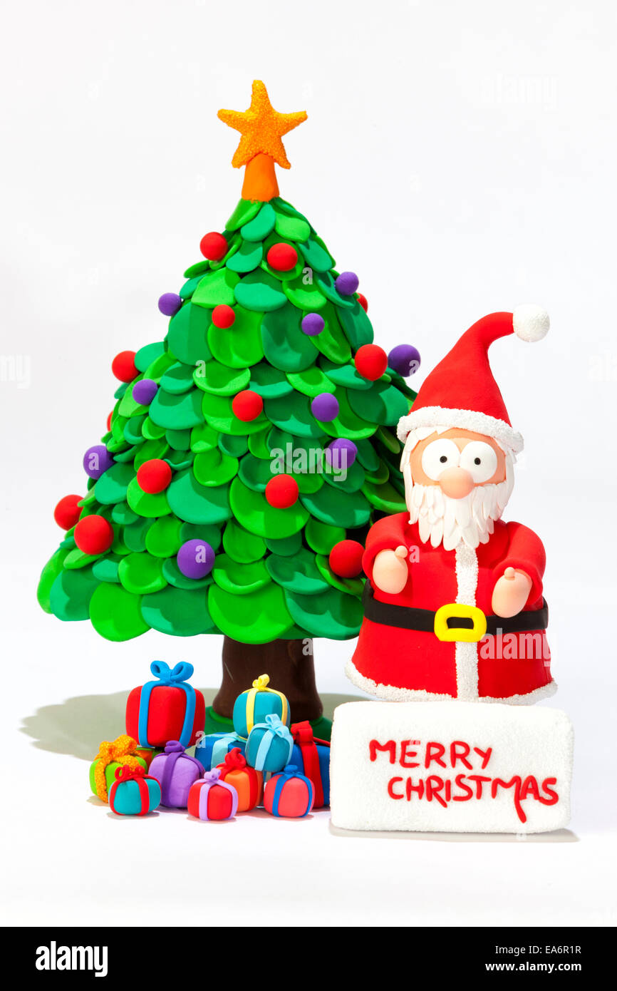 Santa Claus handmade with modeling clay wishing Merry Christmas with a Christmas tree and presents Stock Photo