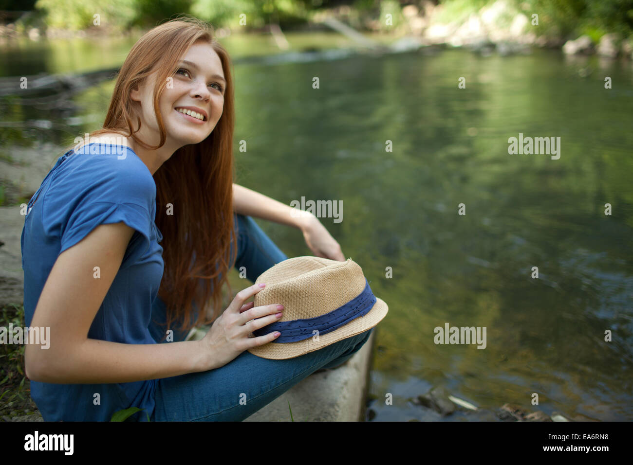 beautiful girl sitting on the bank of the river Stock Photo - Alamy