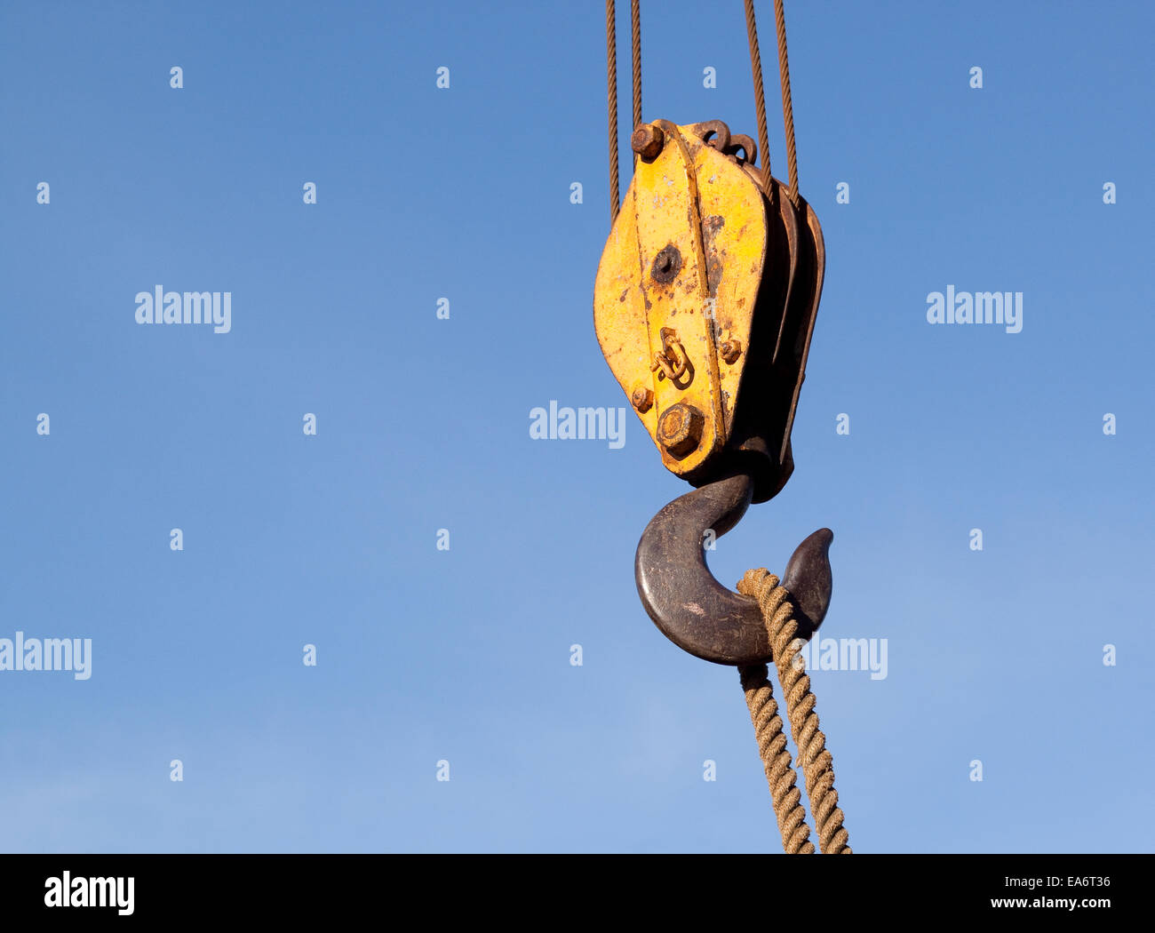 close up of a cable and pulley and hook on a crane on a crane against a clear blue sky raising a rope Stock Photo