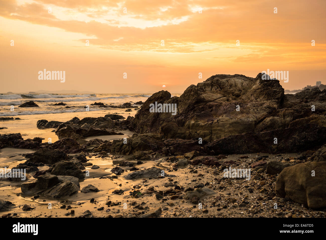 sunset at the rocky beach in cloudy day Stock Photo