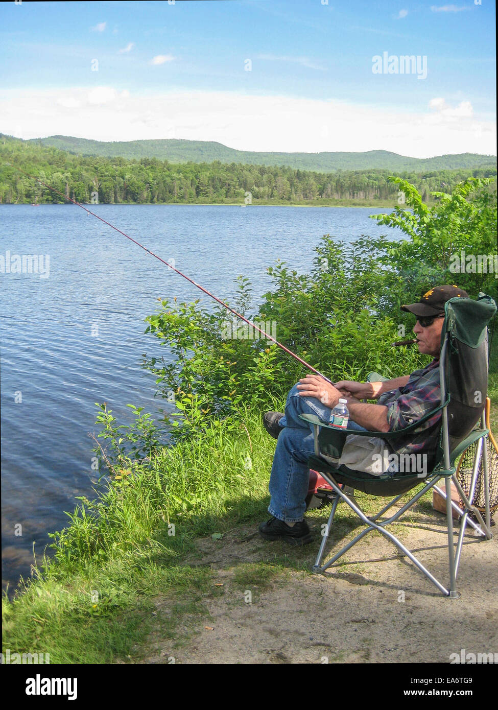 A middleaged senior man relaxes in a soft camp chair smoking a cigar