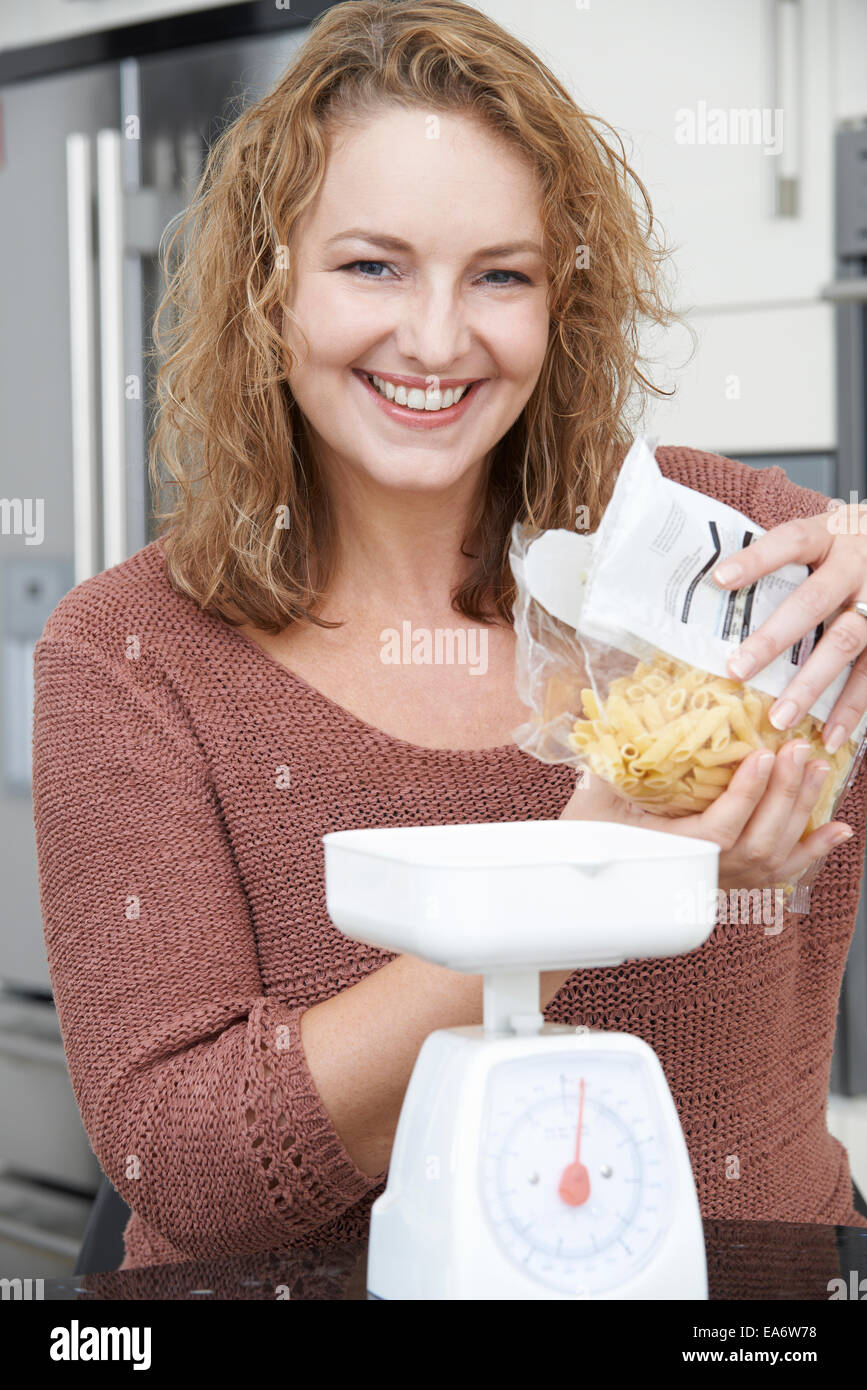 Plus Size Woman On Diet Weighing Out Pasta For Meal Stock Photo