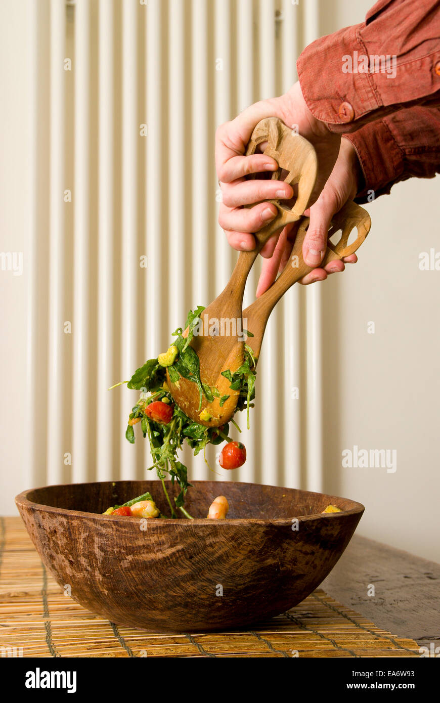 man tossing a green leaves and tomato salad Stock Photo