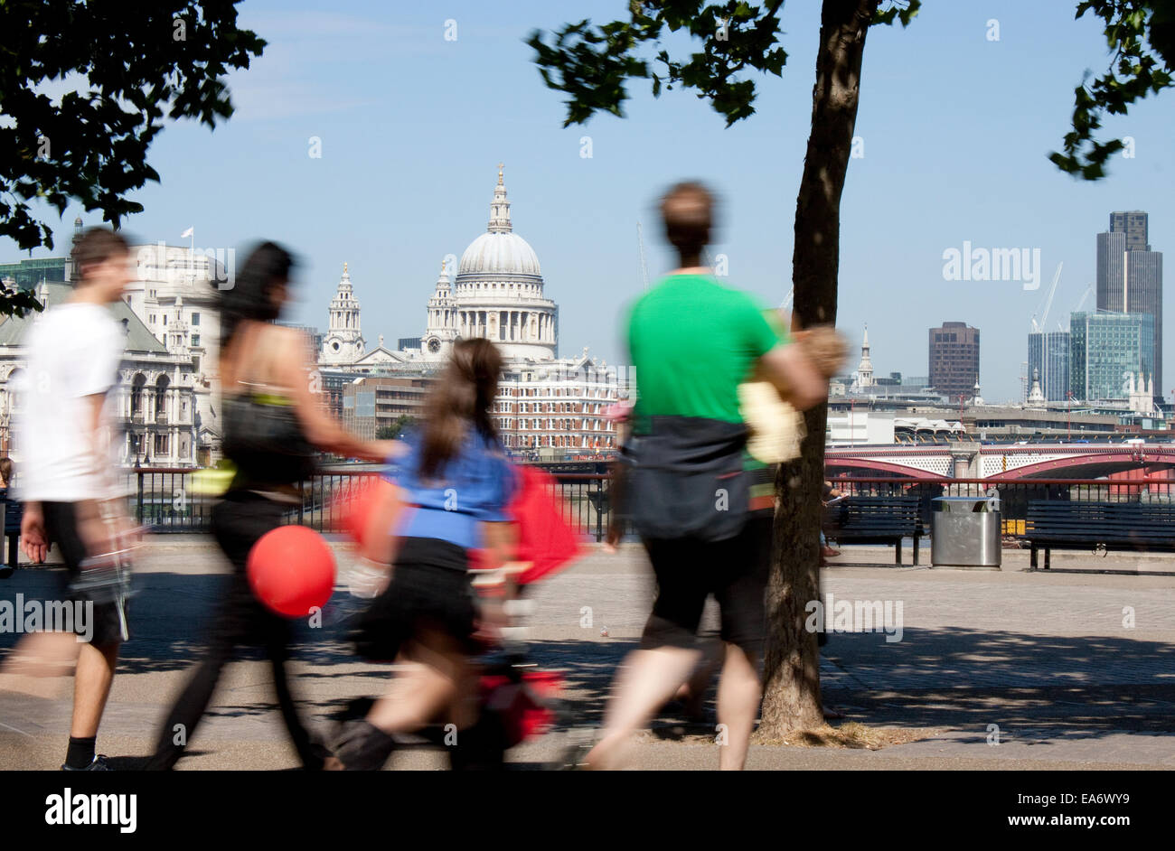 A view of the dome of Saint Pauls Cathedral across the River Thames with motion blurred family group in the foreground Stock Photo