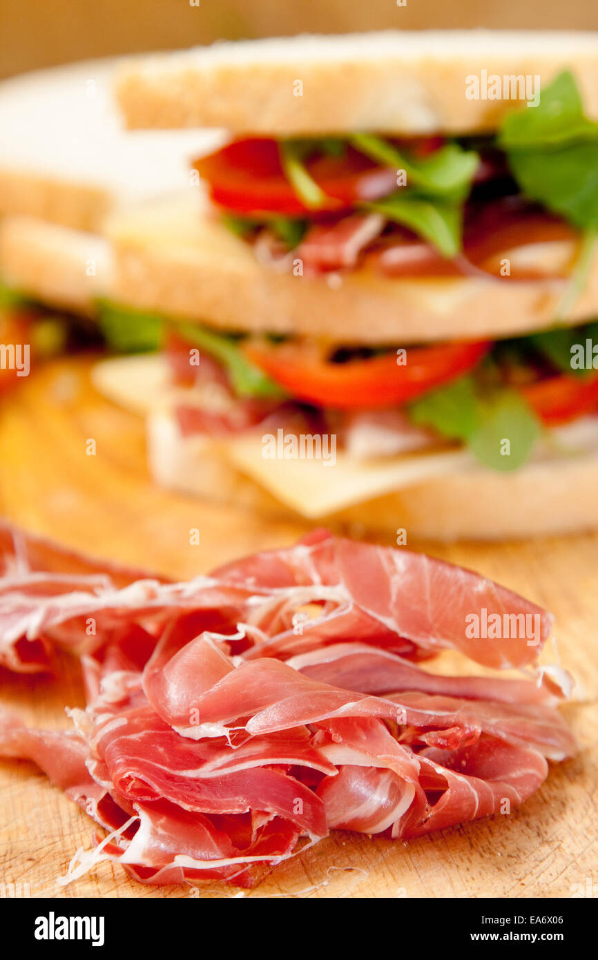 thin slices of Italian prosciutto ham with white bloomer bread sandwich of ham, Gruyere cheese, sliced tomato and rocket Stock Photo