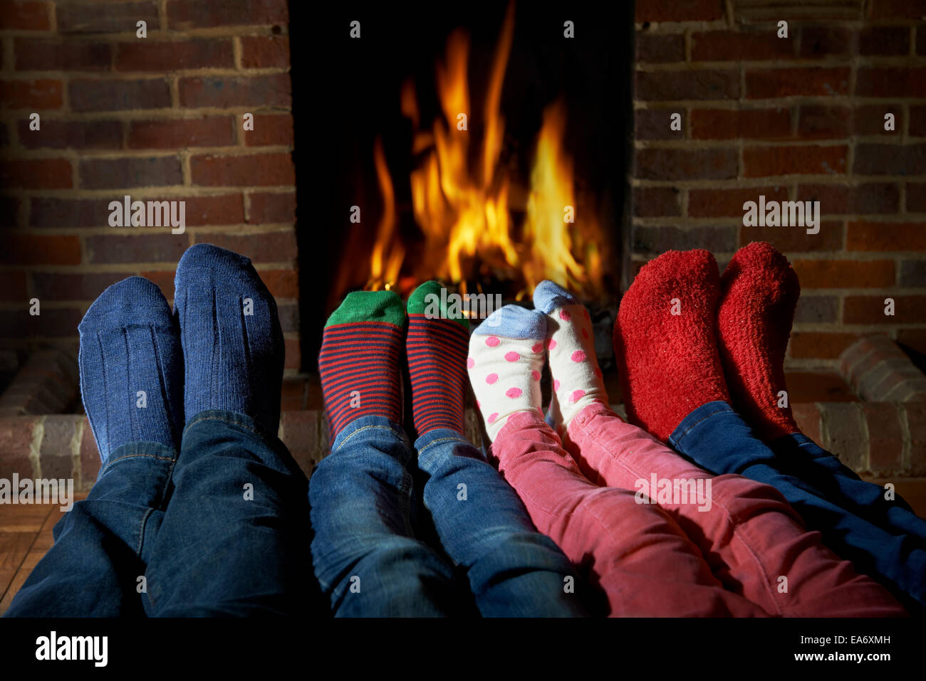 Family Wearing Socks Warming Feet By Fire Stock Photo