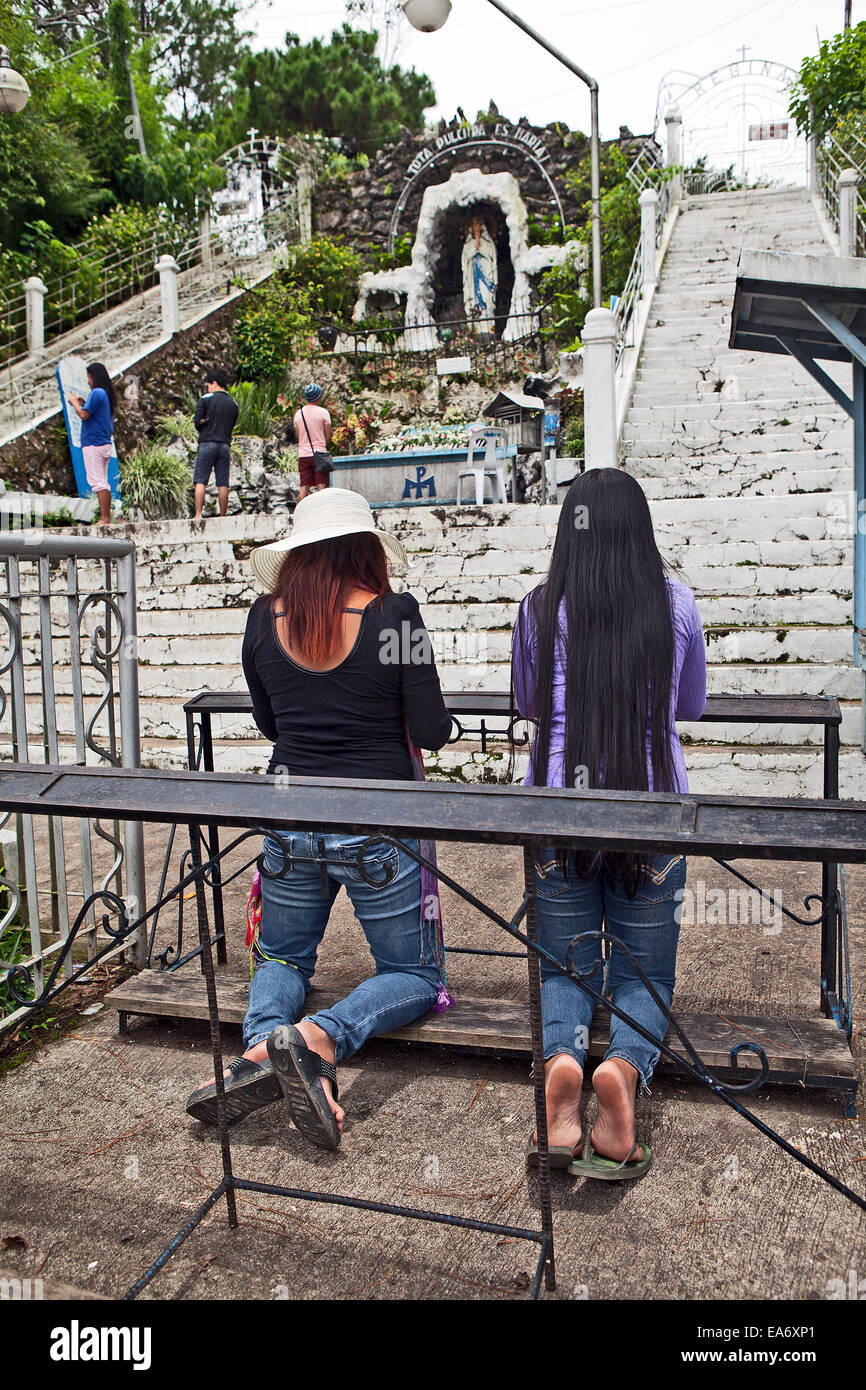 Two Catholic Filipina women pray at the Lady of Lourdes Shrine in Baguio, Philippines. Stock Photo