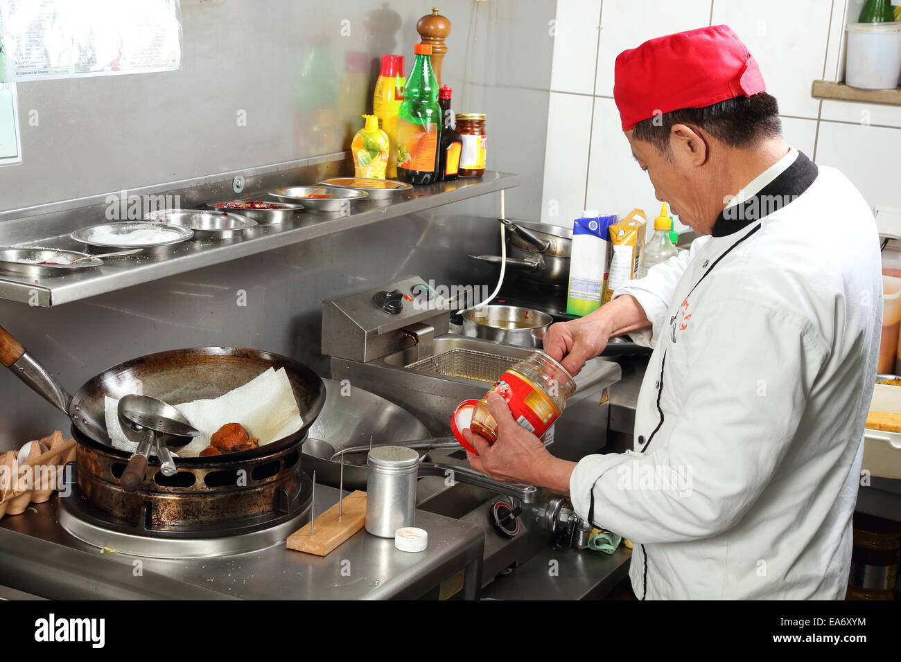 A Asian cook putting spices while cooking Stock Photo