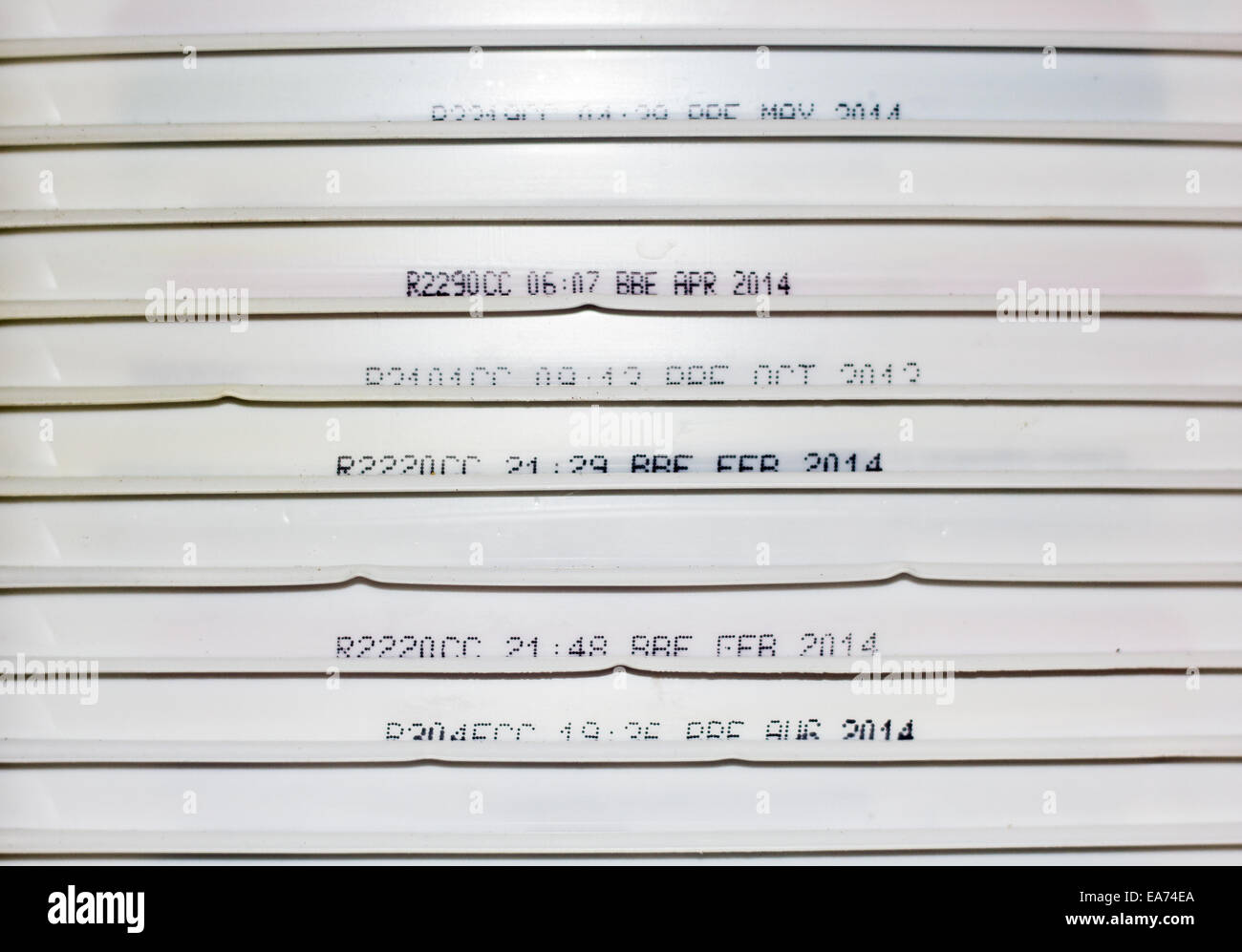 The side of old ice cream tub lids stacked on top of each other, some showing expiry and use by dates. Stock Photo