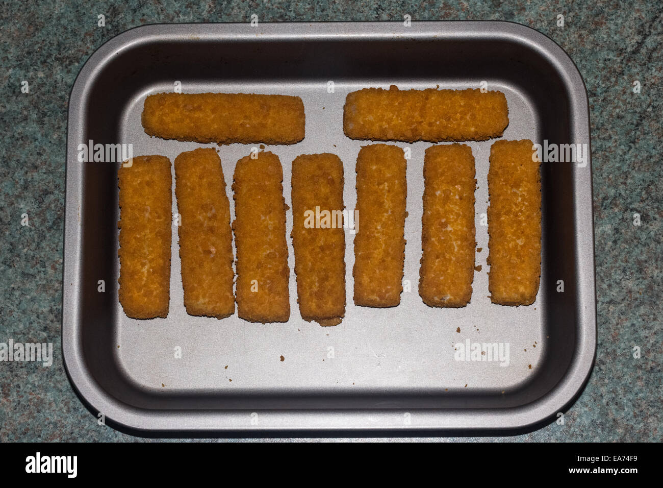 Nine fish fingers on a silver tray ready to be cooked. Stock Photo