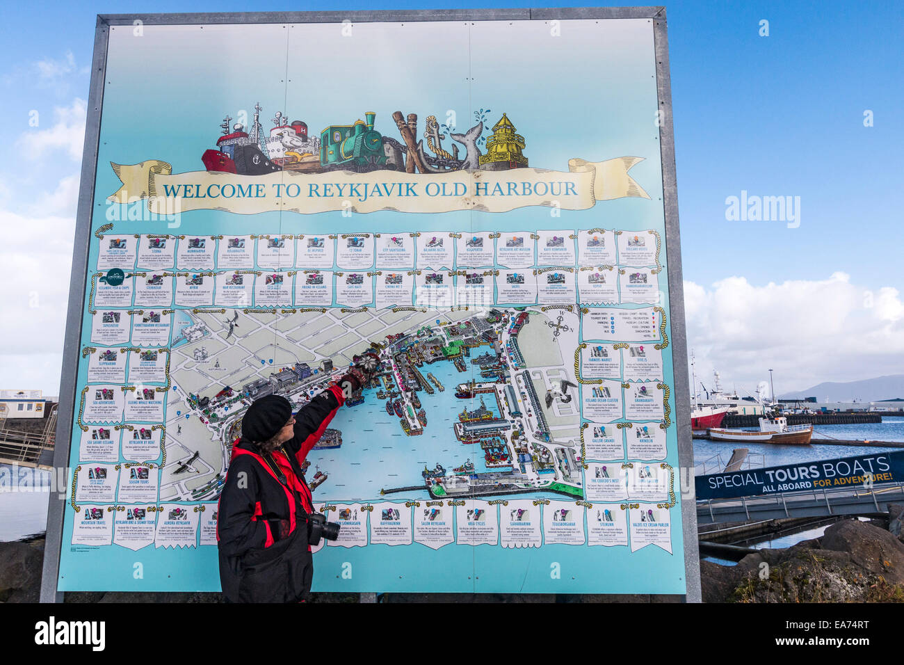 Visitors check out map of Reykjavik's tourist waterfront at the Old Harbour, lined with boats just waiting to take people to see Stock Photo