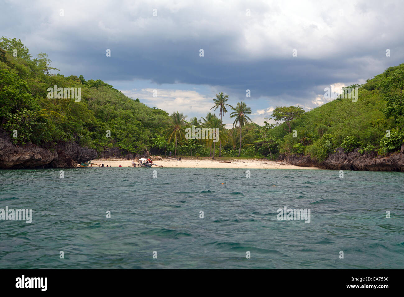 A Filipino tourist boat approaches one of hundreds of remote island beaches in the Guimaras Island Group, Panay Strait, Philippines. Stock Photo