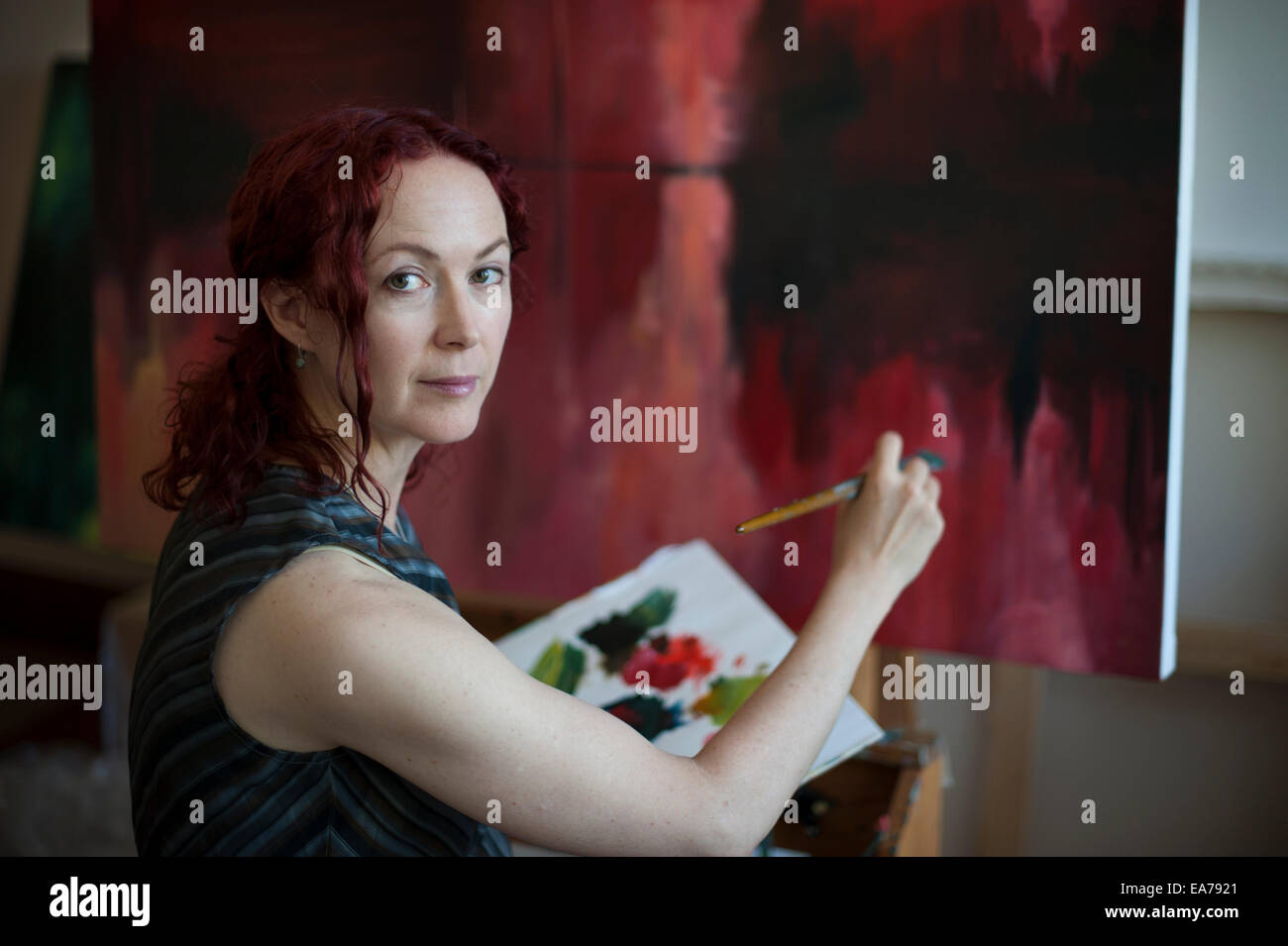 Portrait of middle-aged woman holding palette and painting on canvas Stock Photo