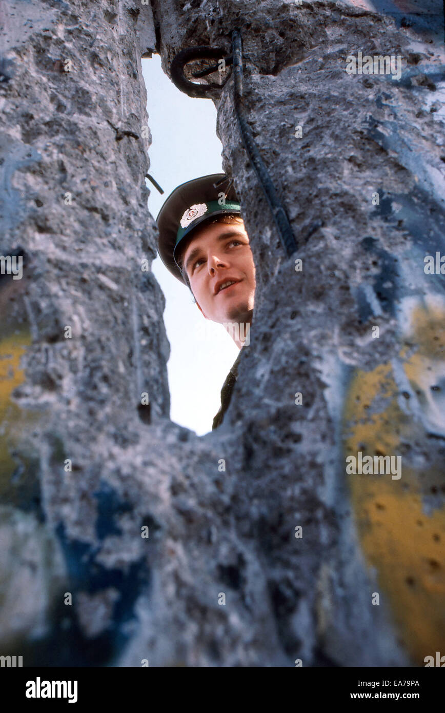 On Sunday, July 9, 2014 marks the 25th anniversary of the fall of the Berlin Wall in Germany that reunited West and East Germany. PICTURED: Nov 23, 1989 - West Berlin, Germany - An East German boarder guard peeks to the west though a hole in the Berlin wall. Westerns began chipping away at the concrete barrier that separated East from West. The collapse of the Soviet Empire lowered the Iron Curtain and unified the two Berlins. © David Becker/ZUMAPRESS.com/Alamy Live News Stock Photo