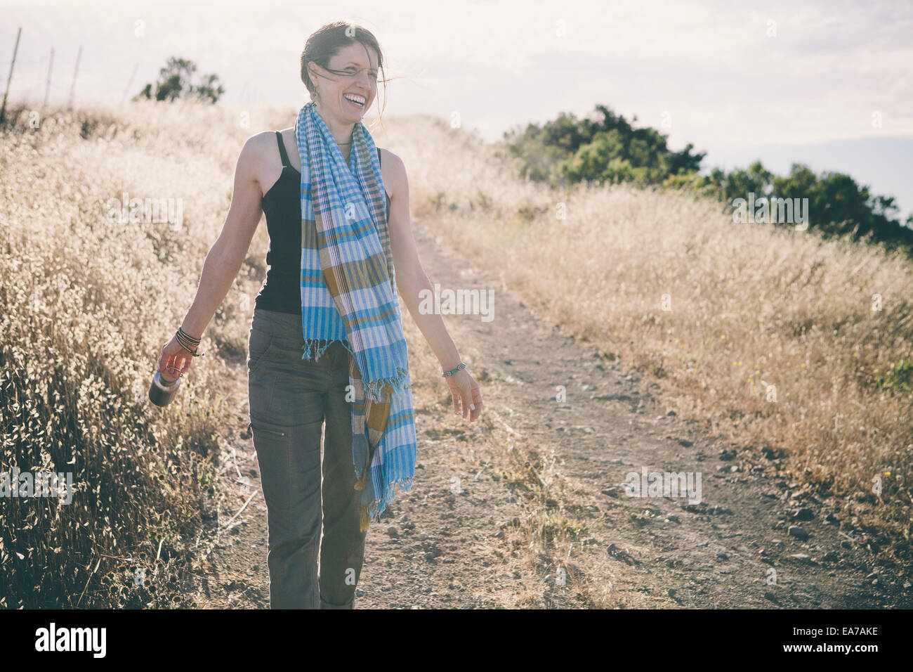 Woman walking on unpaved road and smiling Stock Photo