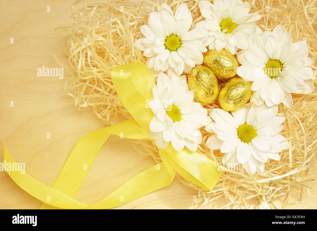 Golden eggs  and flowers in the nest on a wooden background for Easter Stock Photo