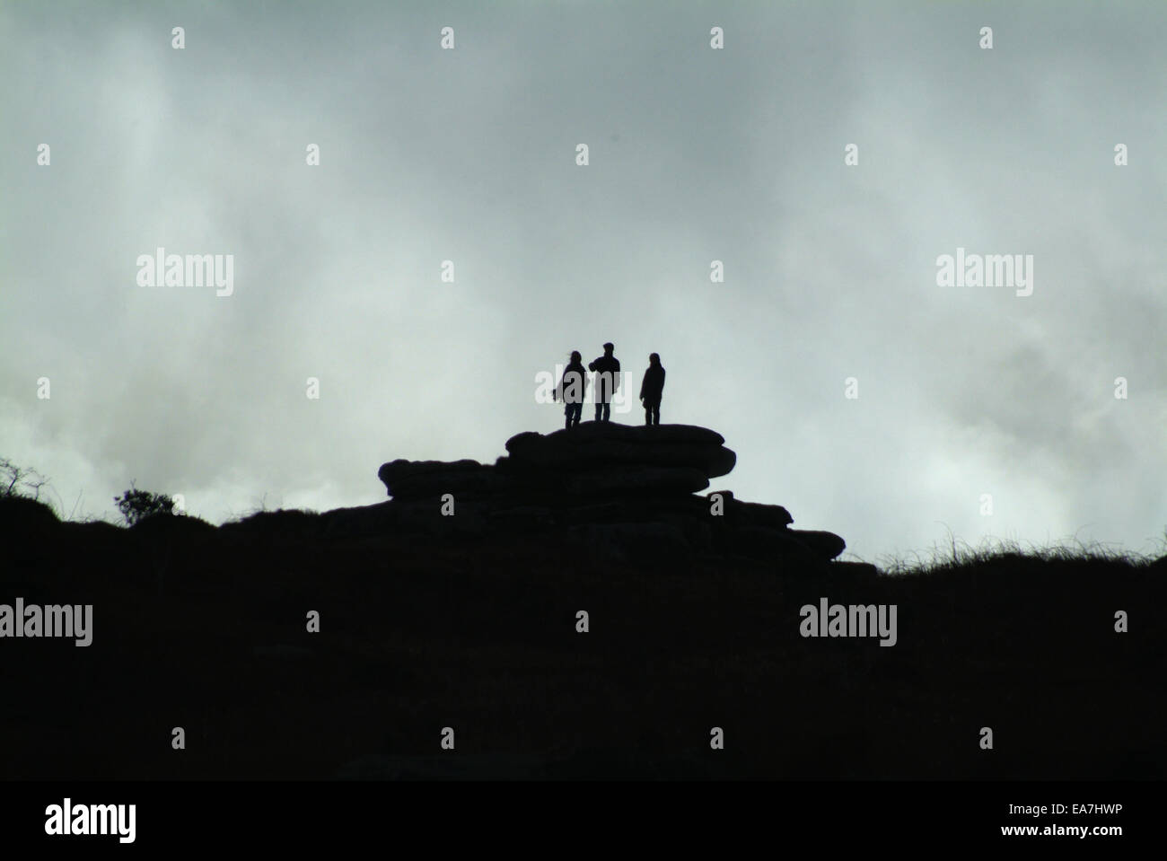 Three Silhouetted figures standing together on top of Trencrom Hill near St Ives Penwith West Cornwall South West England UK Stock Photo