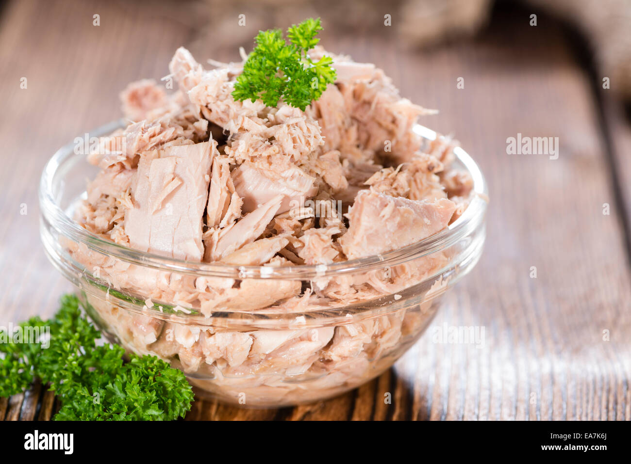 Canned tuna with fresh parsley (detailed close-up shot) on wooden background Stock Photo