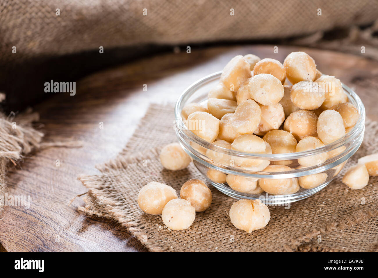 Portion of Macadamia nuts (roasted and salted) on wooden background Stock Photo