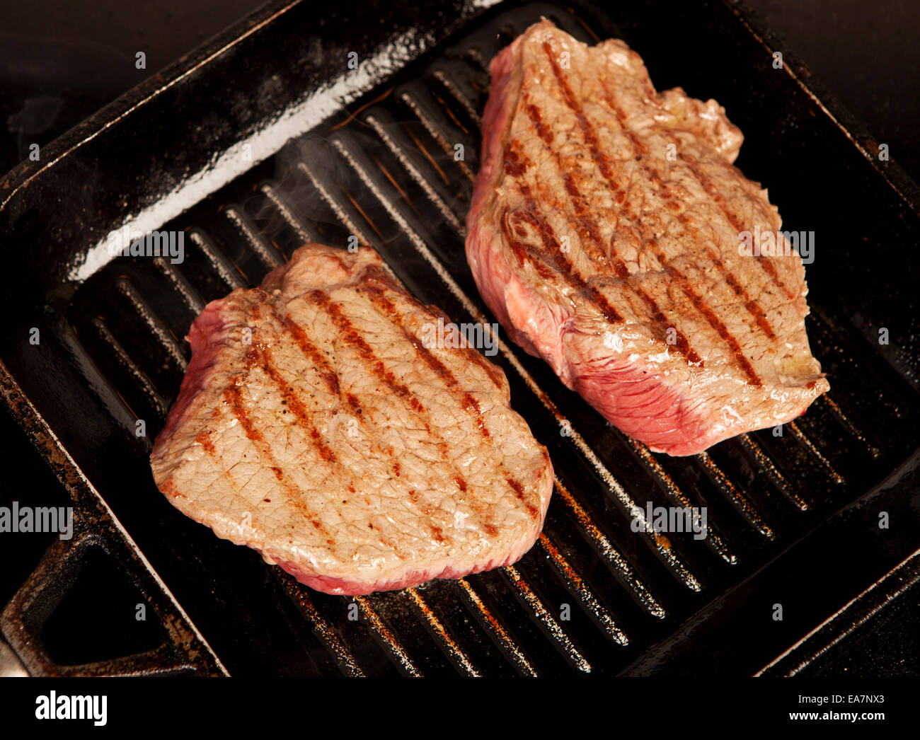 two large slices of beef roast in cast iron pan Stock Photo