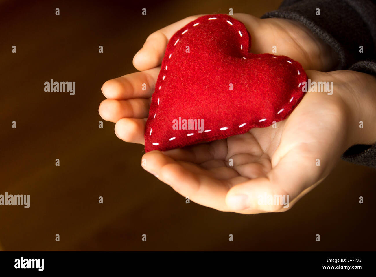 Red heart in child hands, hand made gift, valentine day and family love concept, close up, horizontal Stock Photo