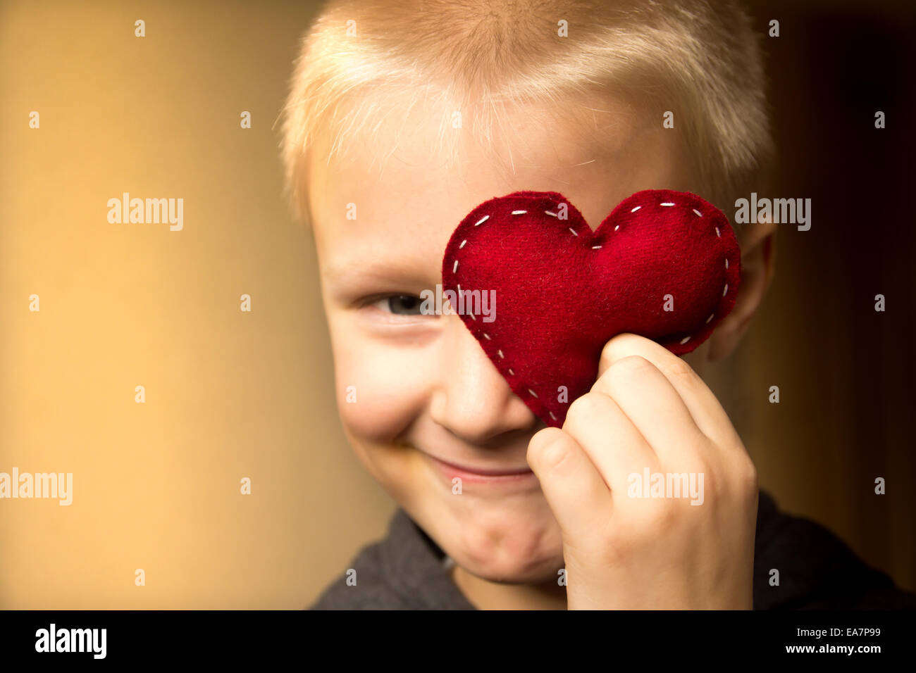 Happy cute child (kid, boy) with hand made red heart. Valentines day and family love concept. Horizontal close up portrait. Stock Photo