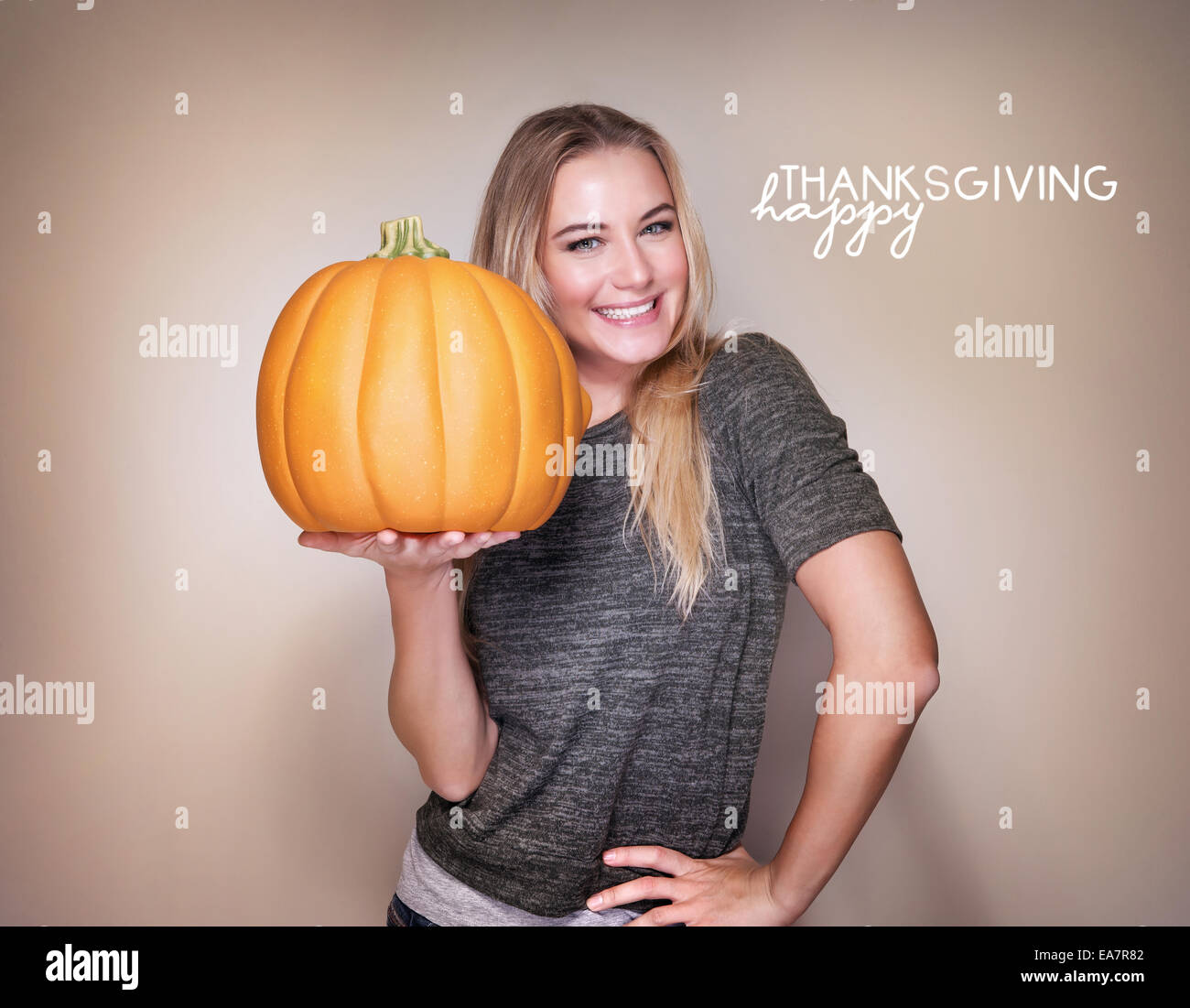 Portrait of beautiful blond woman with big orange pumpkin in hands isolated on beige background, happy Thanksgiving day Stock Photo