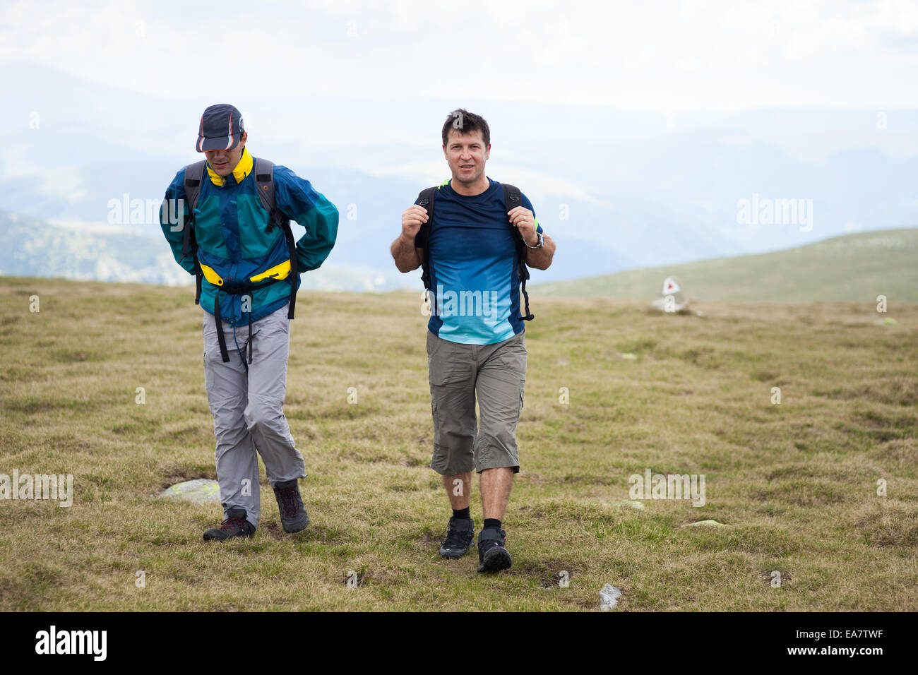Two friends hiking together in mountains, with backpacks Stock Photo ...