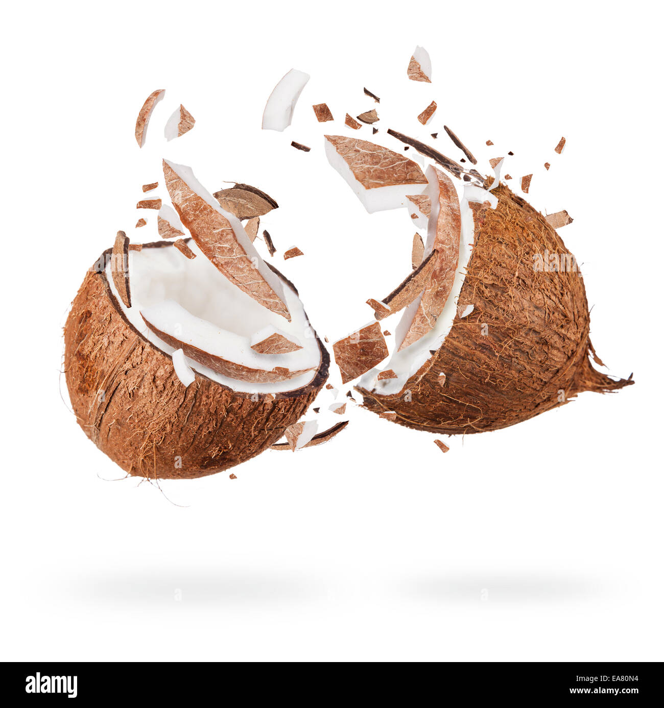 Isolated shot of cracked coconuts with water splash on white background Stock Photo
