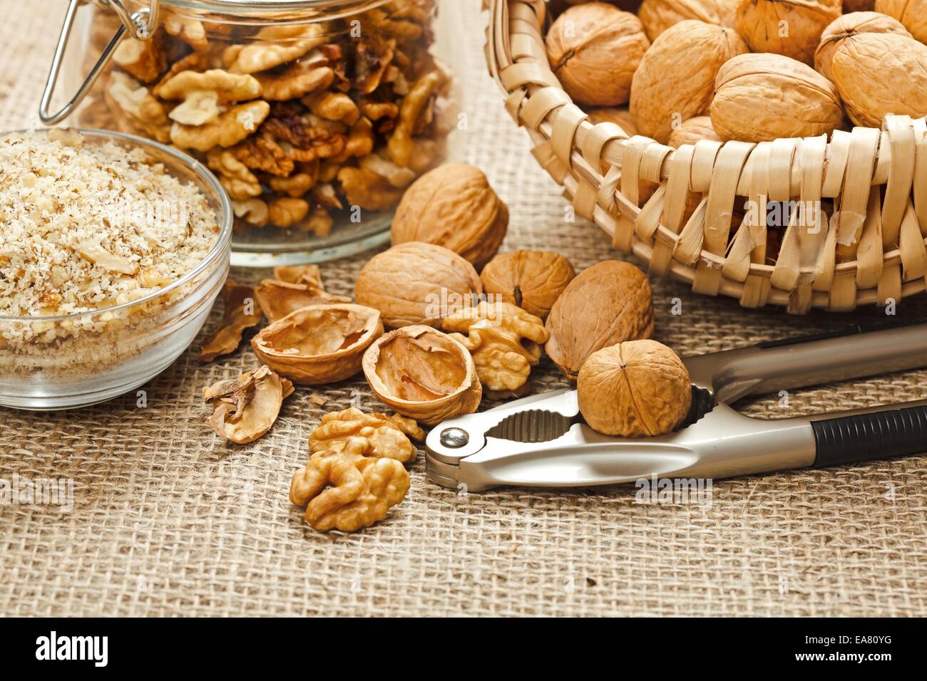 Variations of walnut, minced, whole, cracked, in jar and nut cracker Stock Photo