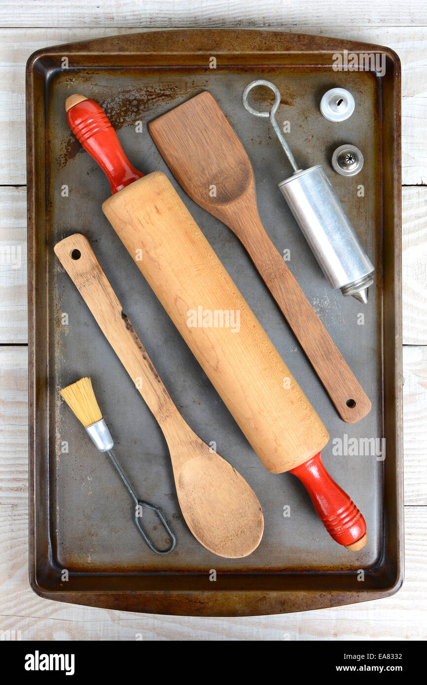 High angle shot of an old baking sheet laid out with tools for baking cookies. The used pan is on a rustic white kitchen table. Stock Photo