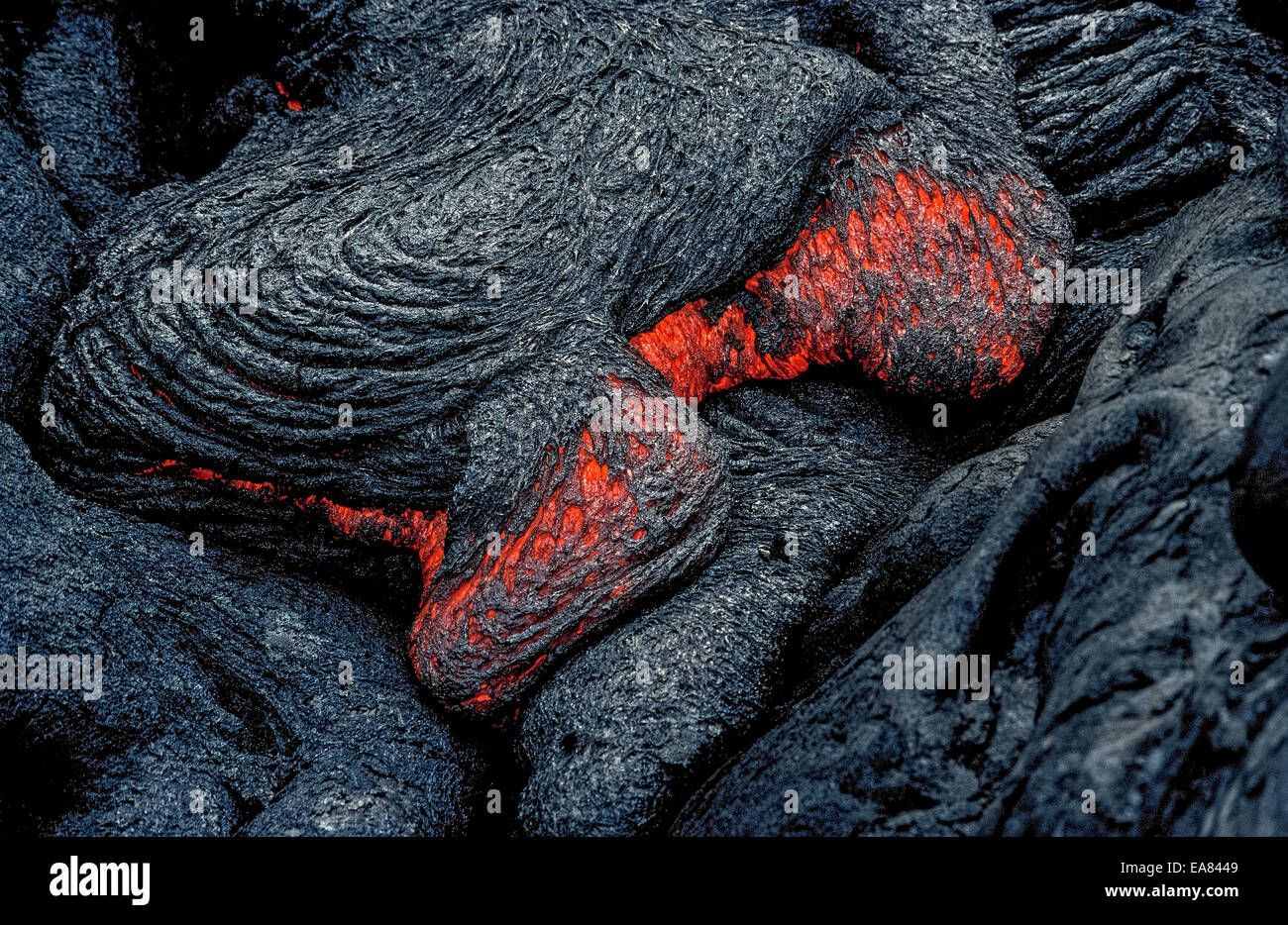 Molten lava rock that glows from its extreme heat flows from an