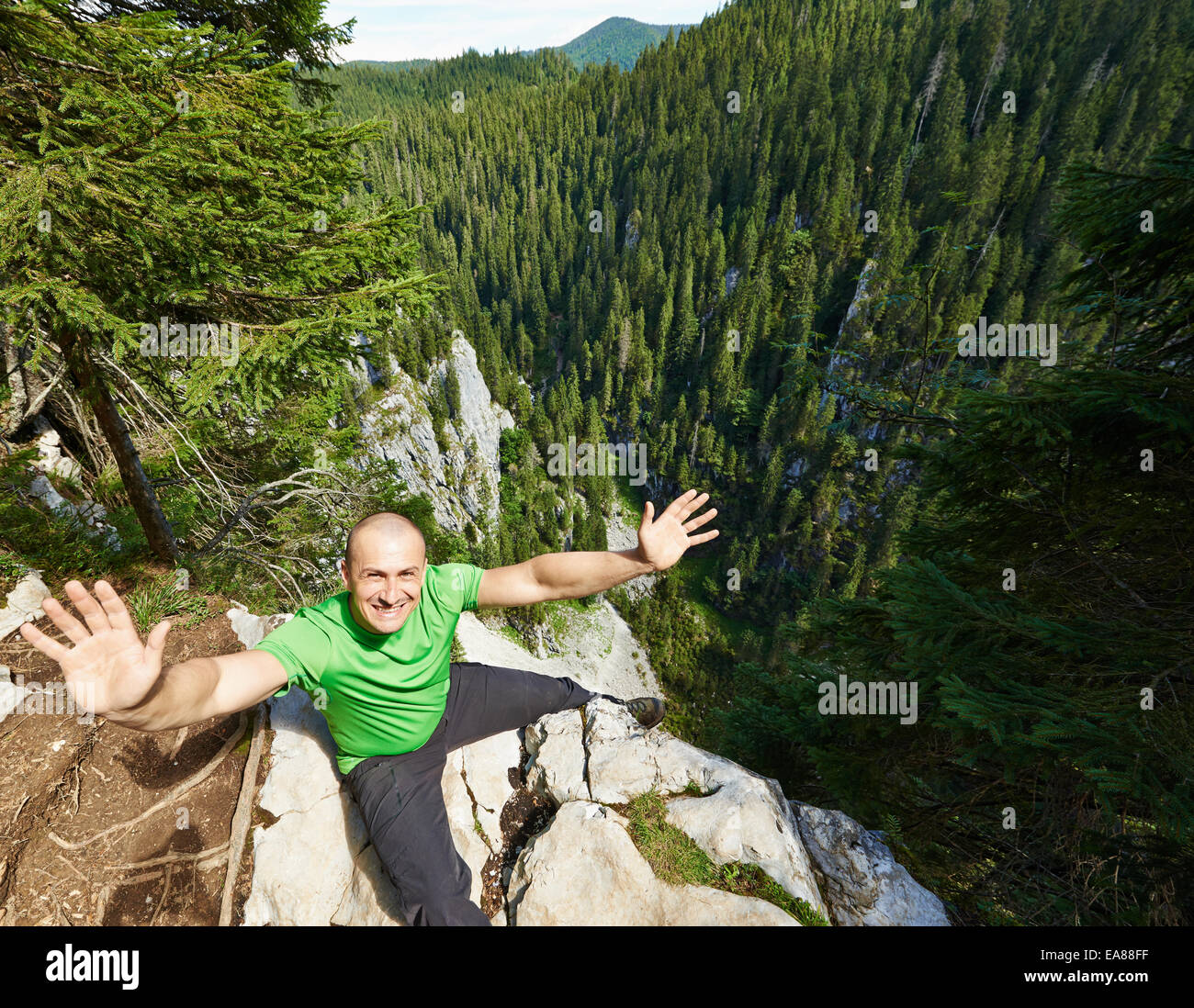 Happy man sitting on the edge of a very high cliff Stock Photo Alamy