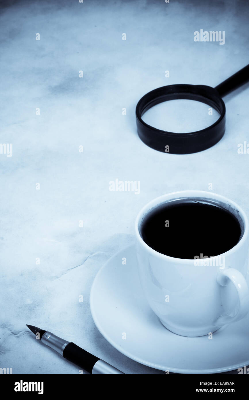 magnifying glass and coffee in blue tint Stock Photo