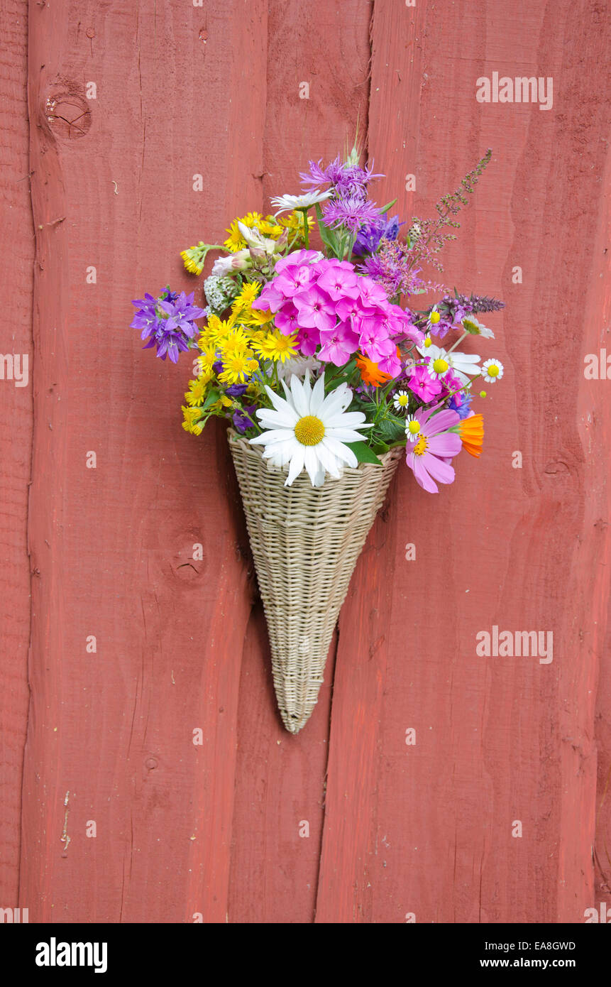 beautiful summer flowers in wicker basket on village farm house wall Stock Photo