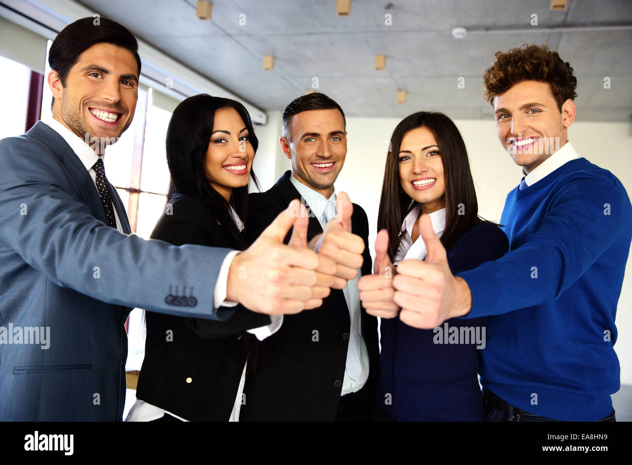 Cheerful young business team with thumbs up sign Stock Photo - Alamy